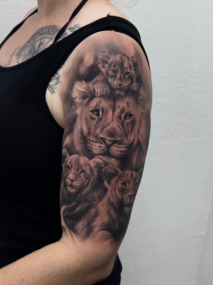 Fotorealistisches Löwenfamilie-Tattoo am Oberarm